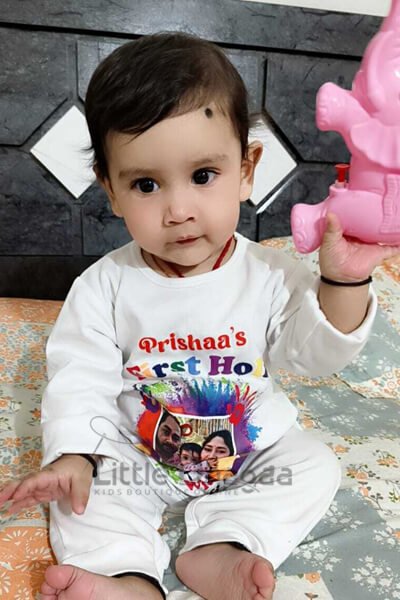 Smiling baby in colorful Holi onesie celebrating first Holi
